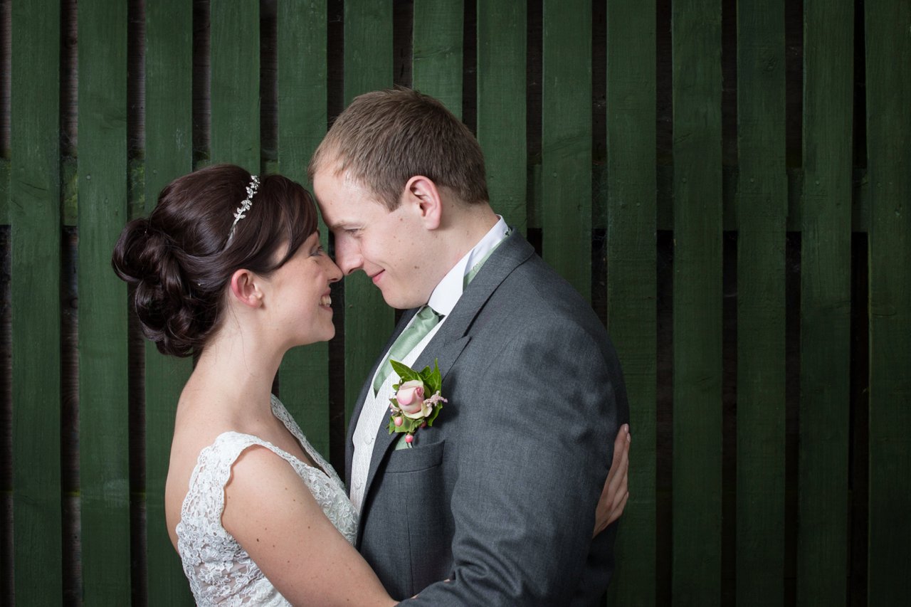 formal bride and groom against green wooden background